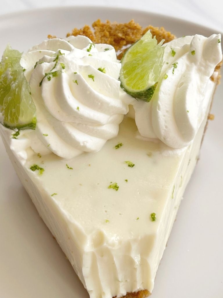 A top shot of key lime pie topped with whipped cream and lime slices.