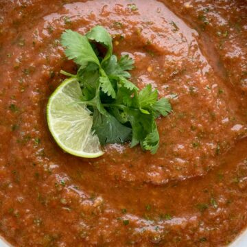 Homemade Salsa with canned whole tomatoes, stewed tomatoes, onion, garlic, jalapeno, cilantro, and seasonings. So simple to make, inexpensive, and it tastes better than anything you'll get at the restaurant or buy in the store. Mild enough for kids but can easily be made spicy!