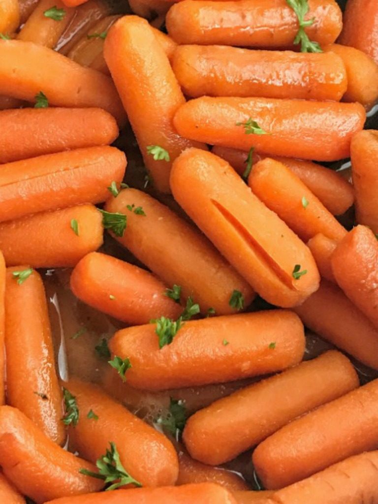 Only 5 ingredients needed for these slow cooker sweet glazed carrots. Perfect side dish that kids and adults will love. Baby carrots simmer all day in chicken broth sweetened with brown sugar and butter! Set it and forget it side dish recipe that is so delicious.