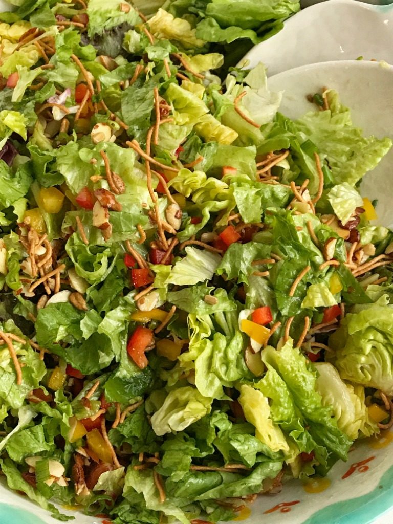 Company green salad is a perfect weeknight side dish or fancy enough for company! Crisp, bright greens with crunchy rice noodles, sweet red & yellow peppers, sugared almonds, salty sunflower kernels, and green onions. Topped with a simple dressing. This salad is surprisingly super easy and the perfect blend of texture, color, and flavor.