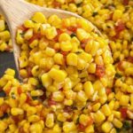 Southwestern corn recipe inside a skillet with a wooden spoon.