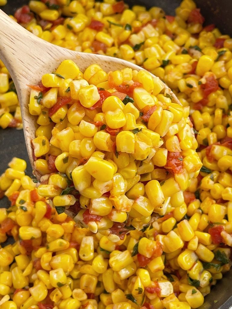 Southwestern corn recipe inside a skillet with a wooden spoon.