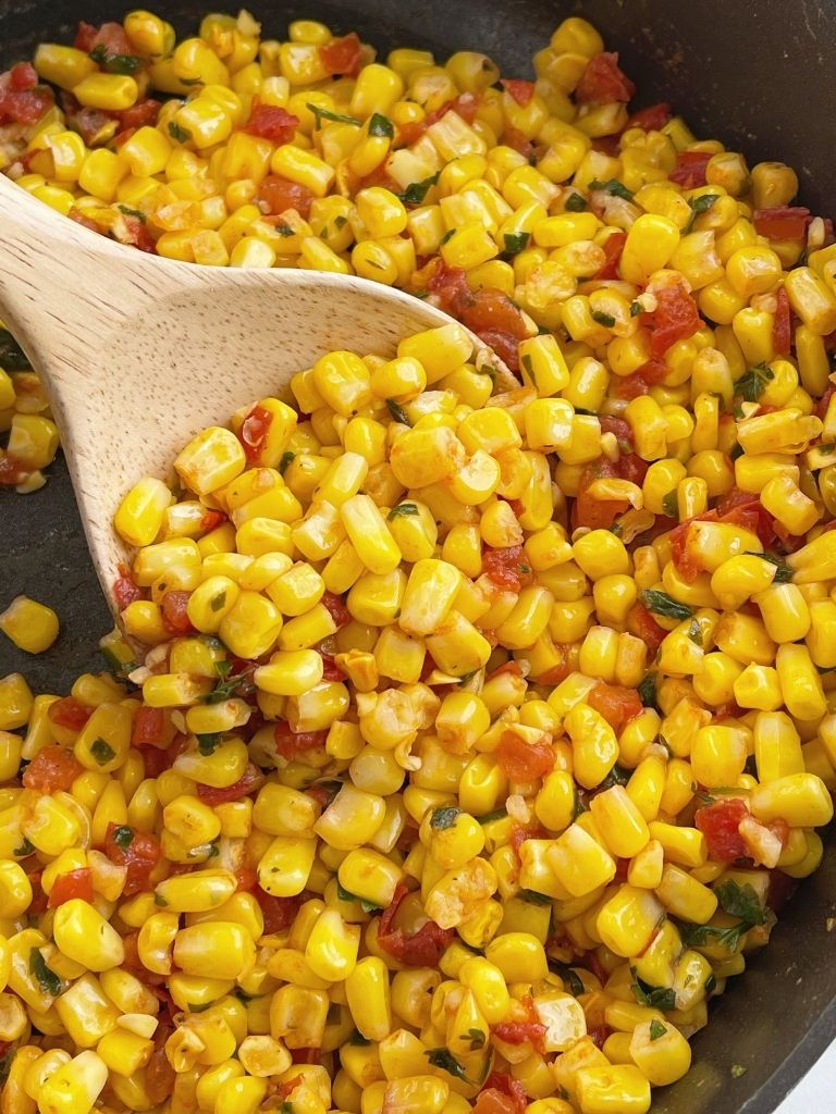Southwestern Corn with a wooden spoon scooping some out.