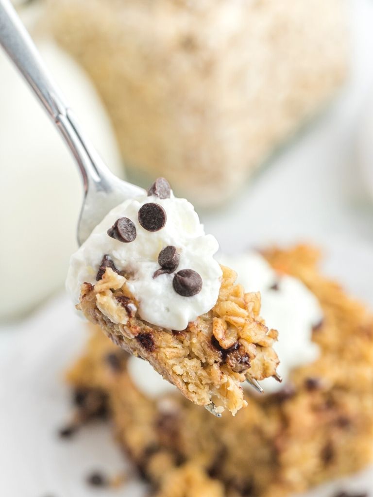 A forkful of baked oatmeal with whipped cream and mini chocolate chips. 