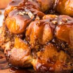 View of the monkey bread with butterscotch glaze on a wooden cutting board.