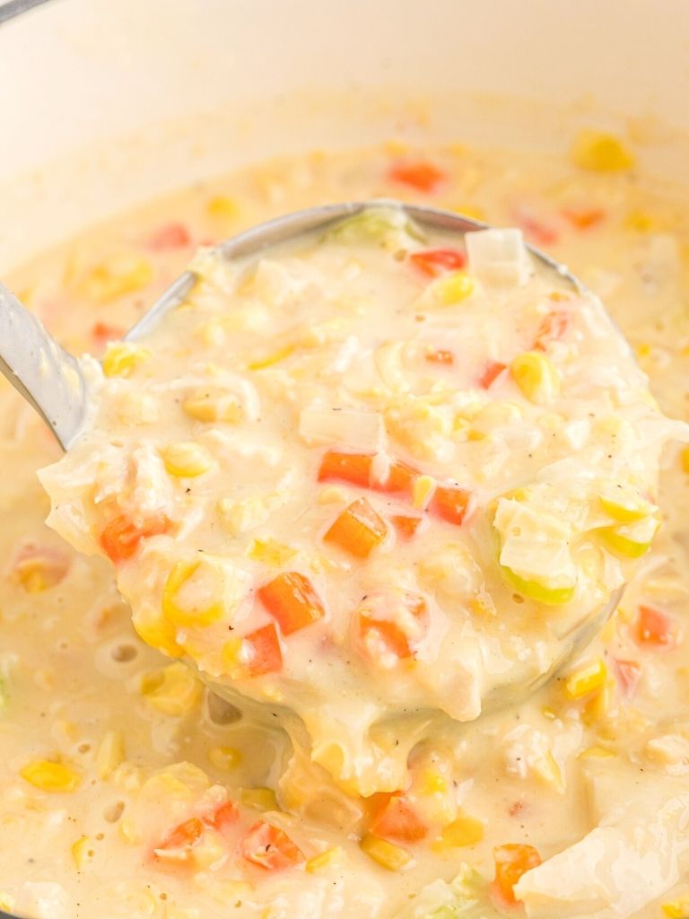A soup ladle with chowder inside of it. 