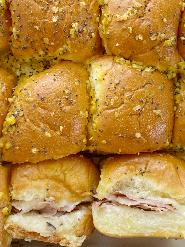 Baked Ham & Cheese Sandwiches are an easy family favorite dinner. Sweet Hawaiian rolls, deli sliced honey ham, shredded swiss cheese slathered in a delicious seasoned buttery sauce. 