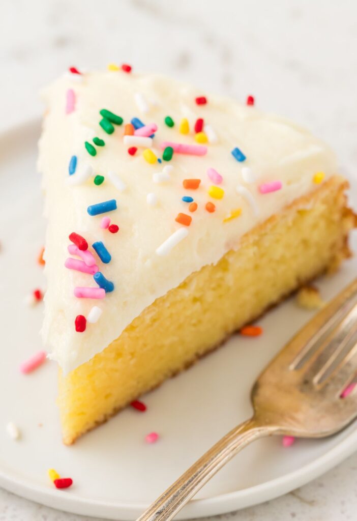 Hero image of a slice of cake with a cake mix and frosting and sprinkles.