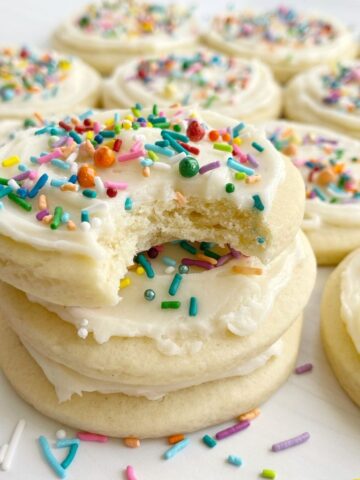 A stack of sugar cookies with a the top cookie having a bite taken out of it.