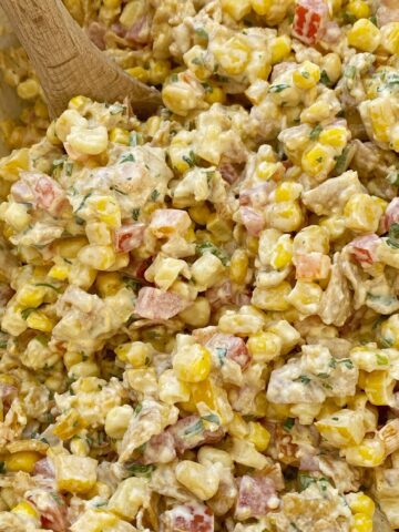 Fritos corn salad with corn, tomatoes, bell peppers, green onion, cilantro, and Fritos in a spiced creamy dressing. This is a salad no one will forget.