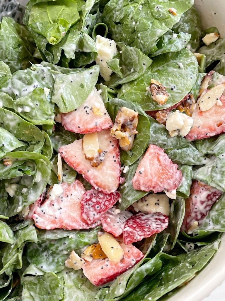 Spinach strawberry salad inside a bowl with homemade strawberry poppy seed dressing.