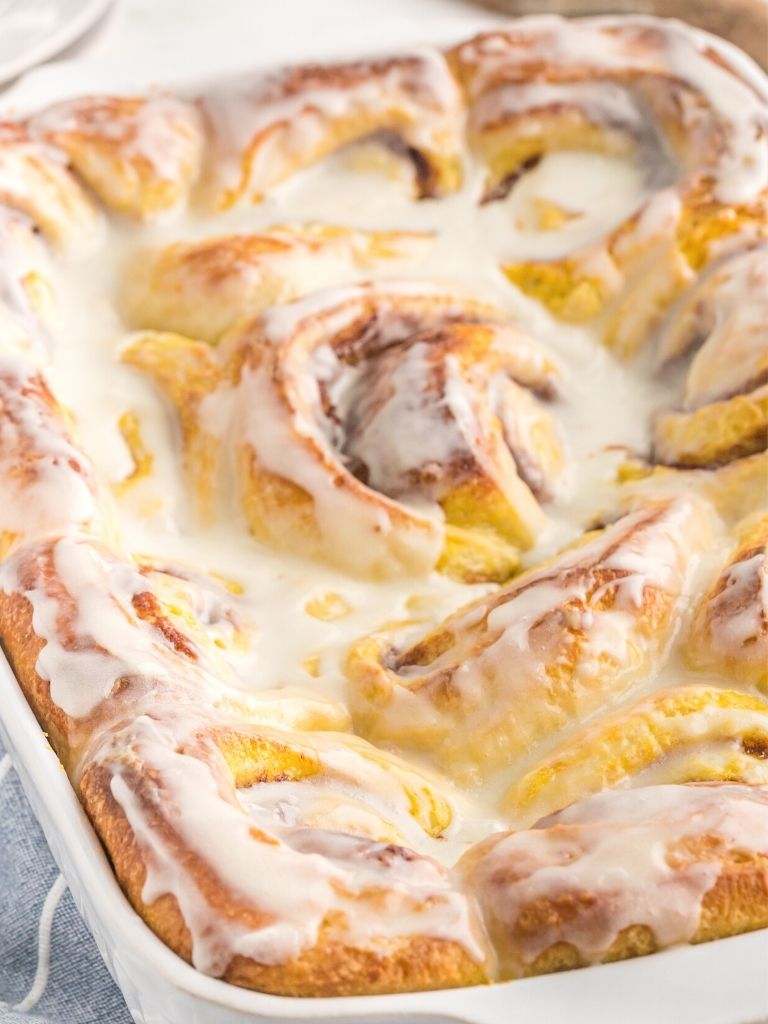 Side shot of a pan of cinnamon rolls with a vanilla glaze on top.