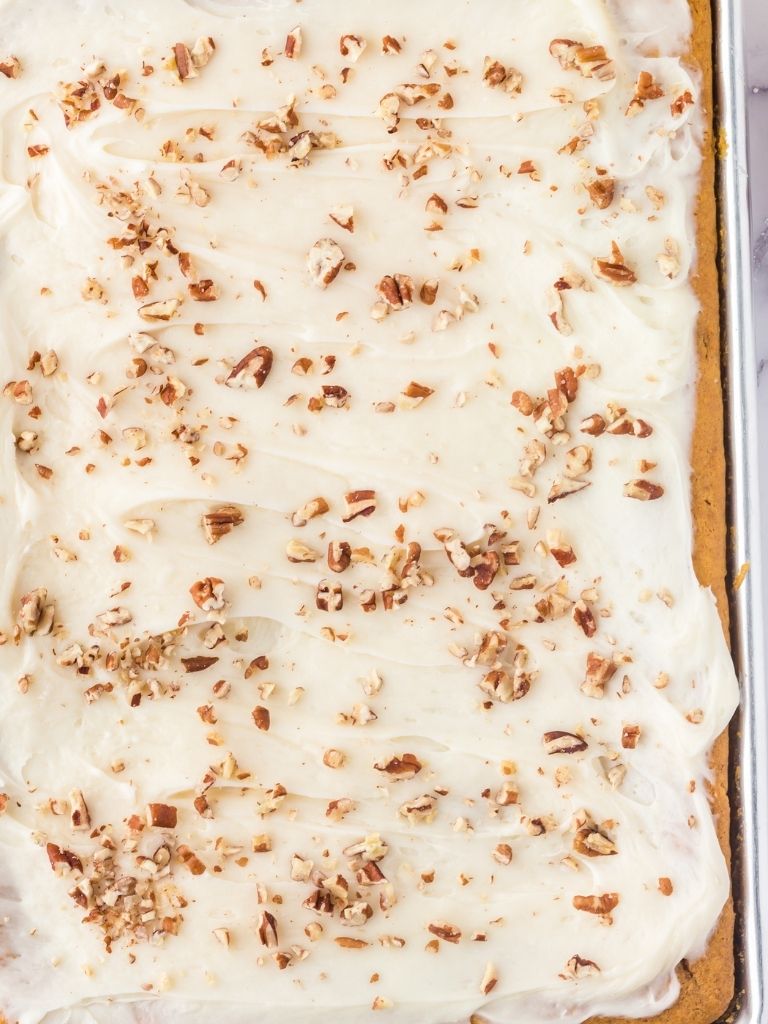Overhead of pumpkin sheet cake topped with pecans.