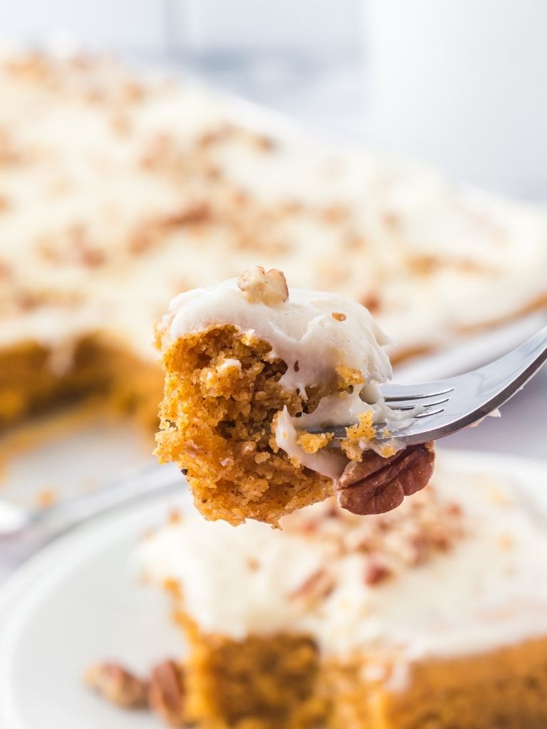 A bite of pumpkin cake on a silver fork with some cake blurred in the background too. 