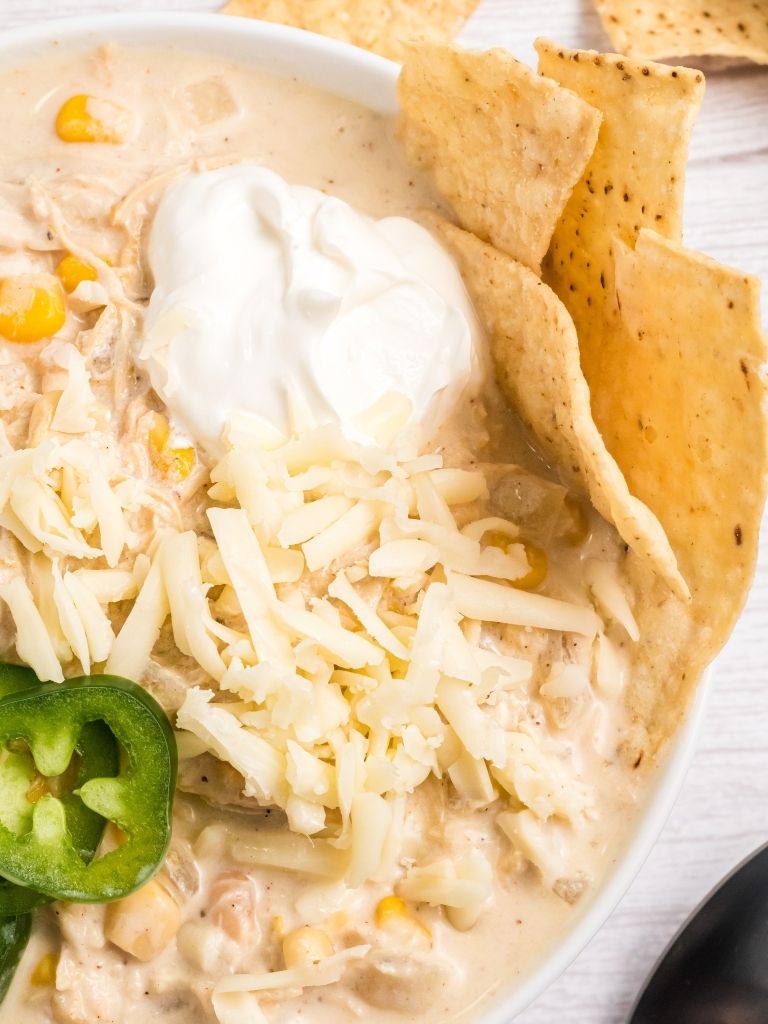 Bowl of white chicken chili with toppings.