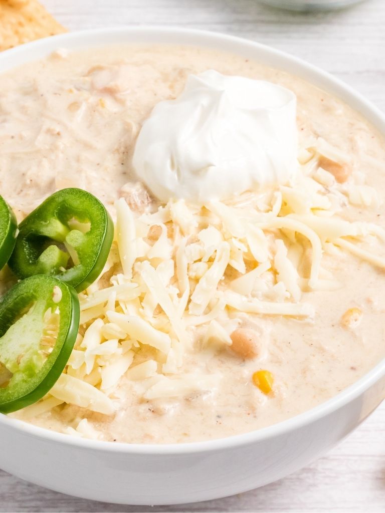 White chili garnished with jalapeño and sour cream.
