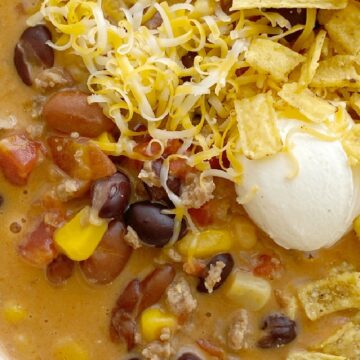 Cheesy Taco Soup is so easy to make in just one pot! Ground turkey, chili beans, black beans, tomatoes, corn, and salsa simmer in chicken broth. Add some Velveeta cheese for the smoothest cheesy taco soup ever.