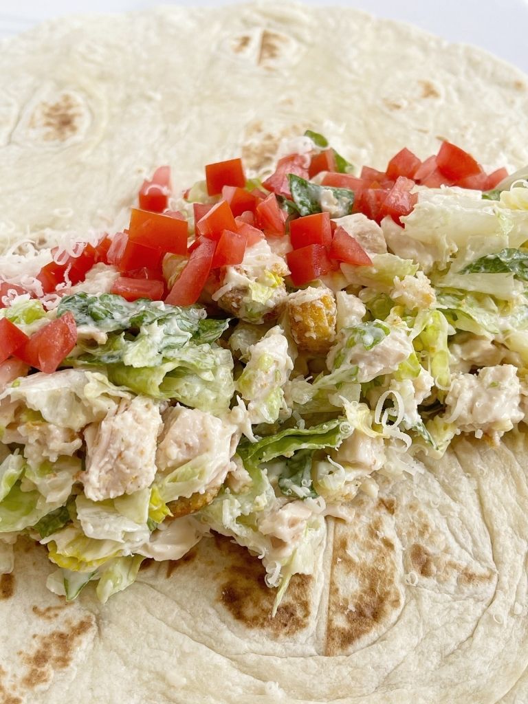 Chicken wraps with Caesar salad dressing and chicken on a flour tortilla. 