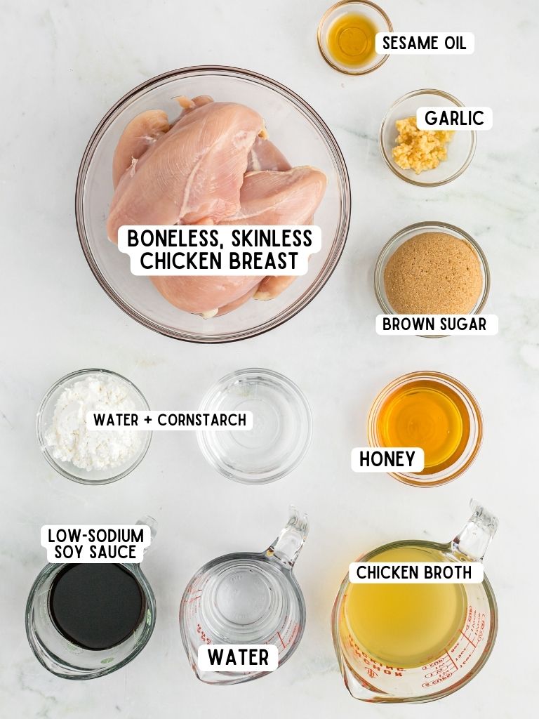 Ingredients needed to make honey teriyaki chicken with each ingredient laying on a white backdrop with a text label with title inside of it. 