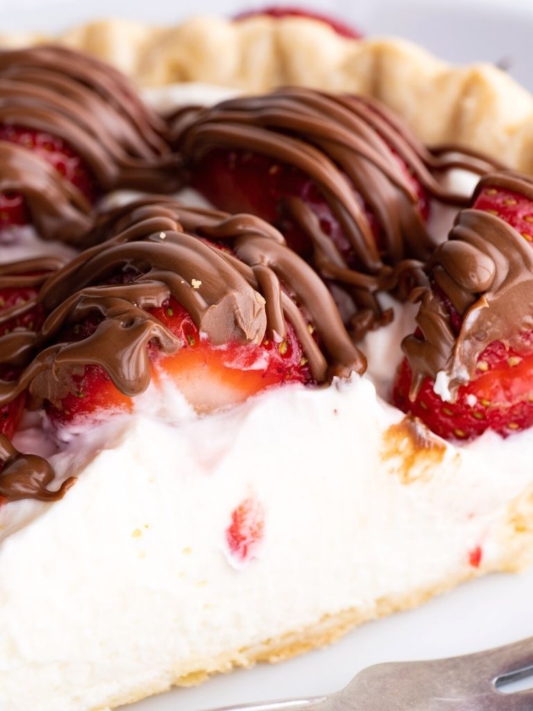 A close up of strawberry pie with a chocolate drizzle over top. 