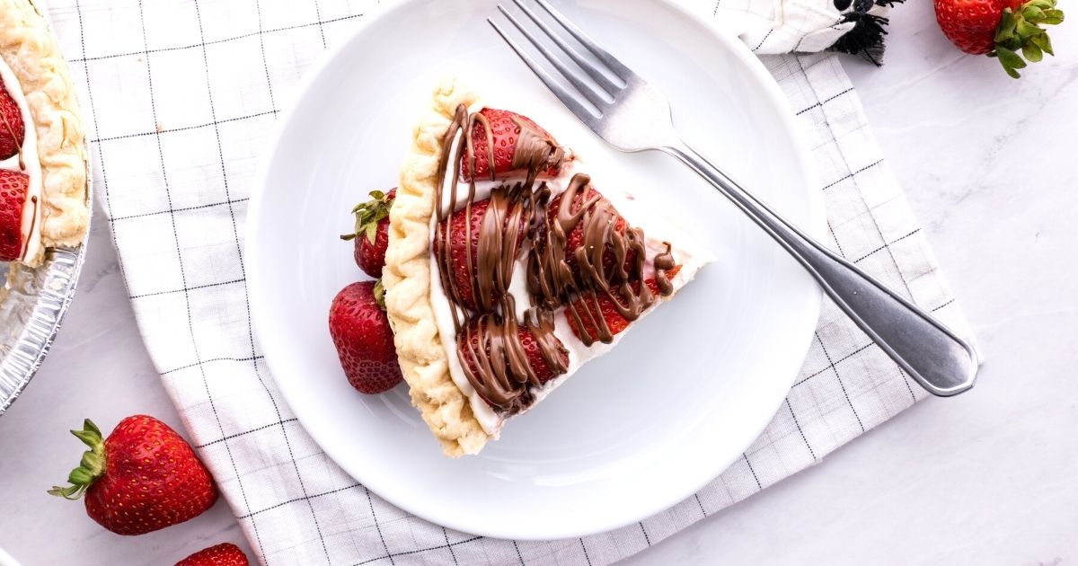 A horizontal image (overhead) of a slice of strawberry pie on a white plate with a fork. 