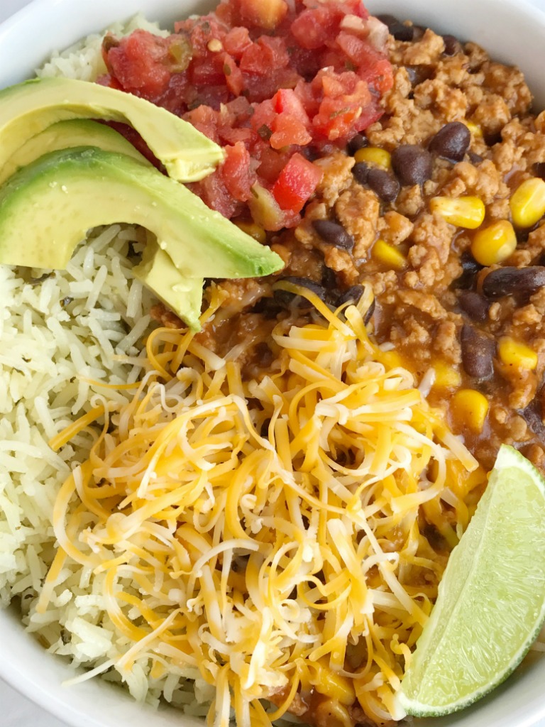 Turkey Taco Burrito Bowls are a family favorite meal! Let everyone build their own bowl for a fun do it yourself dinner. Turkey taco meat simmers on the stove top to make these burrito bowls so flavorful and a quick, 30 minute dinner that everyone will love. Add on all of your favorite taco toppings for a fun and delicious dinner. 