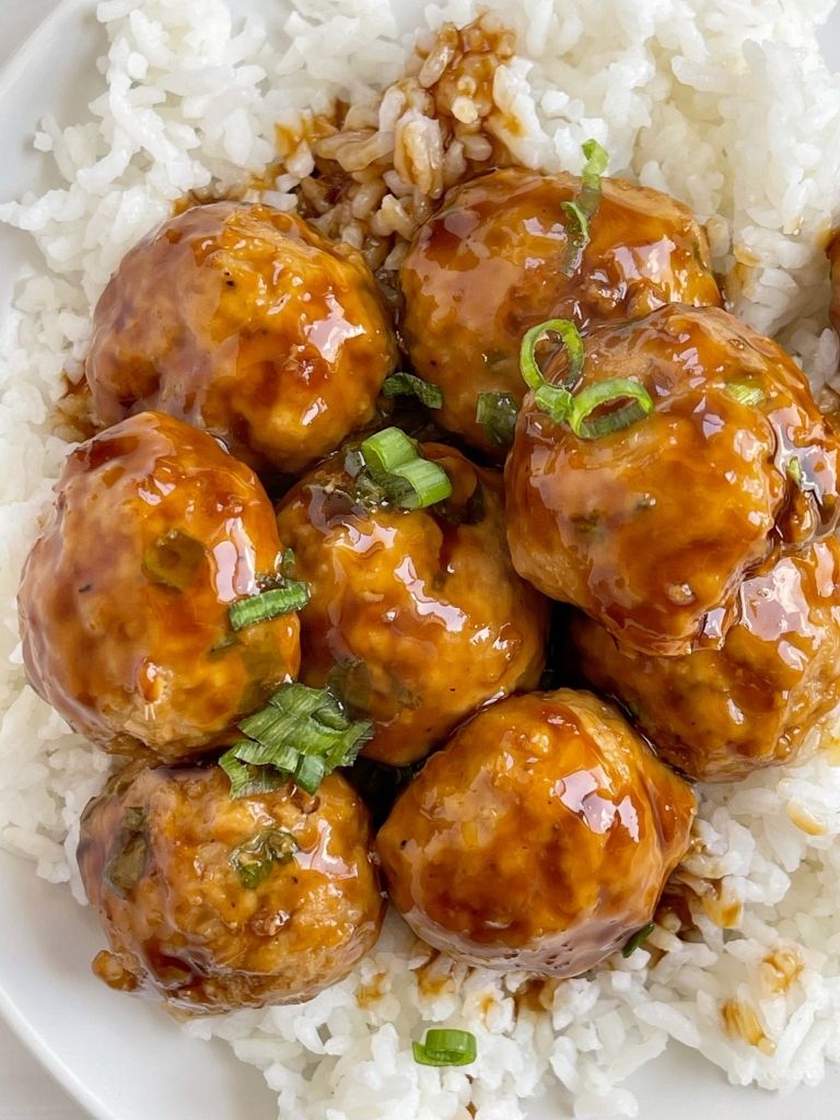Top view of a white plate with chicken meatballs over white rice. 