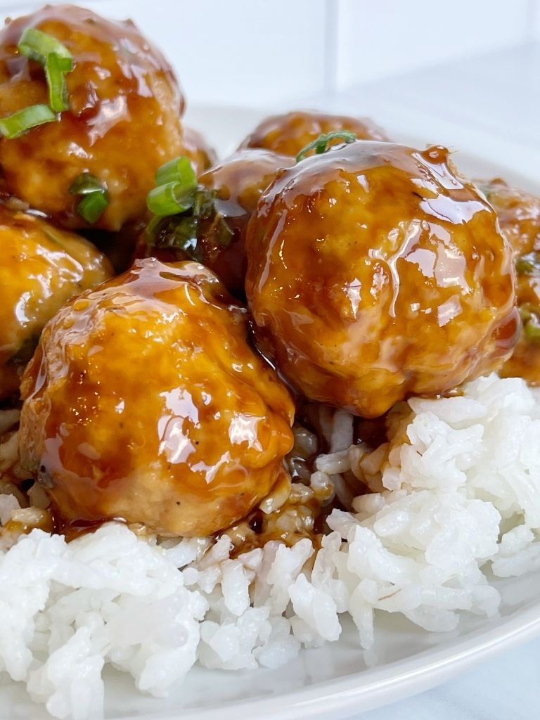 A close view of teriyaki chicken meatballs over rice. 