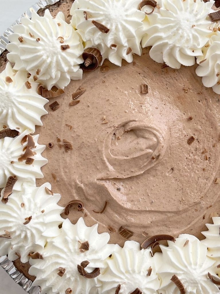 A double chocolate cream pie topped with whipped cream on a white background.
