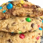 Giant Reese's stuffed monster cookies are the most delicious & indulgent dessert! Cookies bigger than your hand that are loaded with oats, peanut butter, chocolate chips, mini m&m's. The best part is the Reese's peanut butter cup stuffed inside.