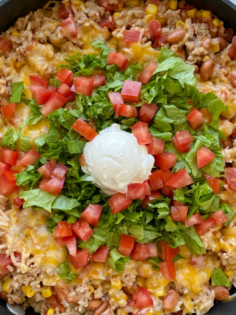 Turkey Taco Rice Skillet is a one pan dinner that's loaded with ground turkey, beans, corn, tomatoes, rice, cheese, and seasonings. Simmers in beef broth for an easy skillet dinner recipe with ground turkey.