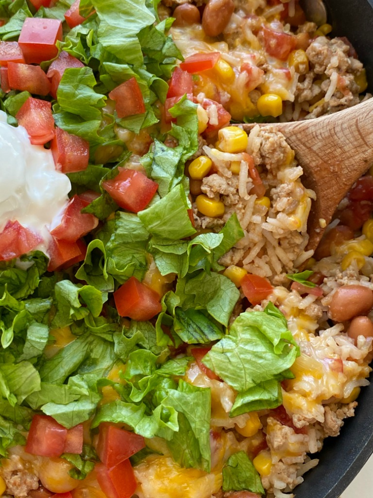 Turkey Taco Rice Skillet is a one pan dinner that's loaded with ground turkey, beans, corn, tomatoes, rice, cheese, and seasonings. Simmers in beef broth for an easy skillet dinner recipe with ground turkey.