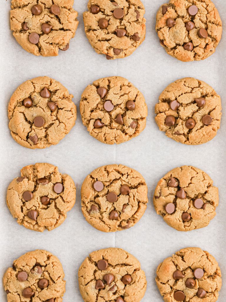 Overhead picture of cookies on a parchment lined cookie sheet that have been baked. 