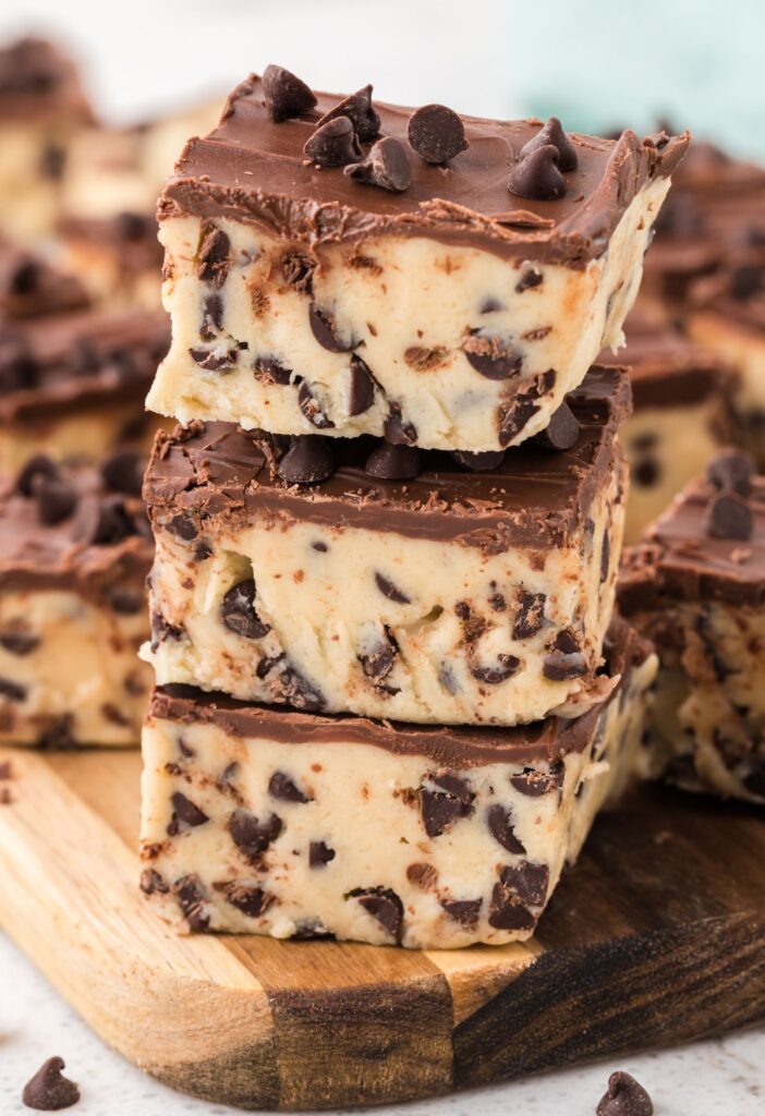 Stack of the cookie dough bars on a wooden cutting board. 