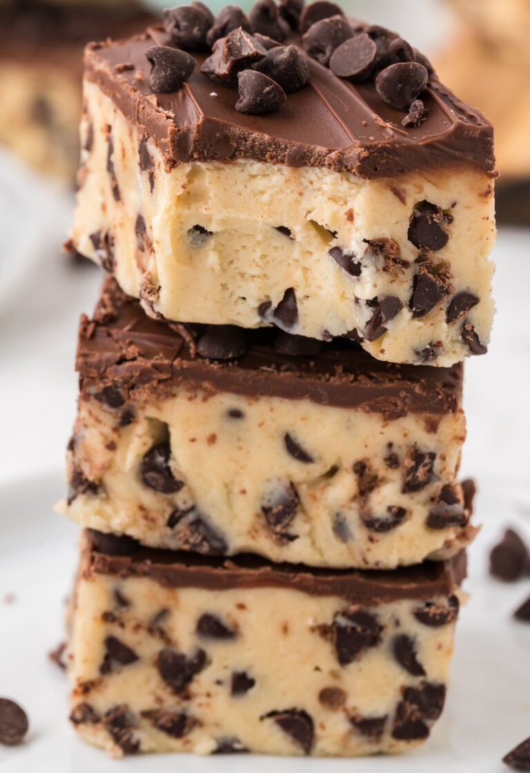 Stack of squares of cookie dough bars with the top piece having a bite taken out of the corner.