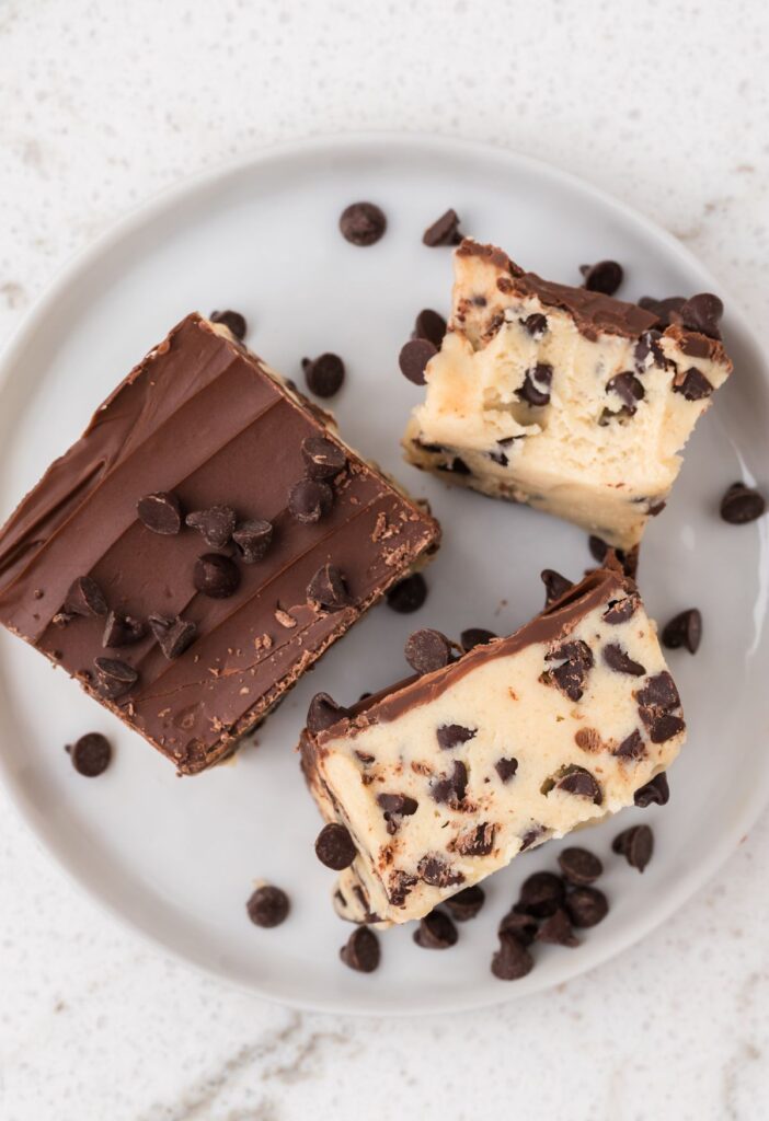 White plate with pieces of the cookie dough bars on it. 