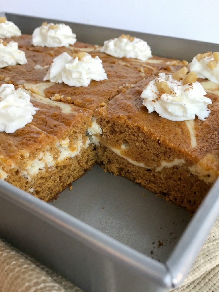 Cheesecake swirl pumpkin cake is a moist and flavorful pumpkin cake loaded with warm pumpkin spices and has a sweet cheesecake swirl. Garnish with whipped cream and chopped pecans for a delicious pumpkin dessert recipe | www.togetherasfamily.com #pumpkin #pumpkincake #dessert #recipe