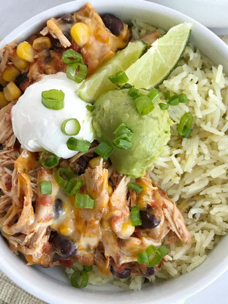 Slow cooker chicken taco burrito bowls are a fuss-free, minimal prep & ingredients, and a family favorite dinner recipe. Cheesy chicken taco meat is made in the slow cooker! Create your very own burrito bowl, at a fraction of the cost of take-out, right at home. Cheesy chicken taco meat served over some cilantro lime rice and topped with avocado, sour cream, green onions, and whatever else you want | www.togetherasfamily.com #chickenrecipes #tacorecipes #tacos #slowcookerrecipes #crockpotrecipes #burritobowls 