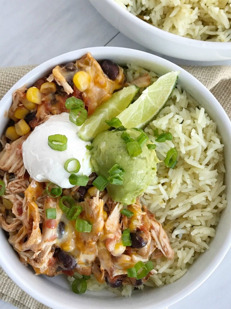 Slow cooker chicken taco burrito bowls are a fuss-free, minimal prep & ingredients, and a family favorite dinner recipe. Cheesy chicken taco meat is made in the slow cooker! Create your very own burrito bowl, at a fraction of the cost of take-out, right at home. Cheesy chicken taco meat served over some cilantro lime rice and topped with avocado, sour cream, green onions, and whatever else you want | www.togetherasfamily.com #chickenrecipes #tacorecipes #tacos #slowcookerrecipes #crockpotrecipes #burritobowls 