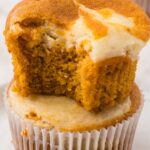 A stack of two muffins with the top one with a bite out of it