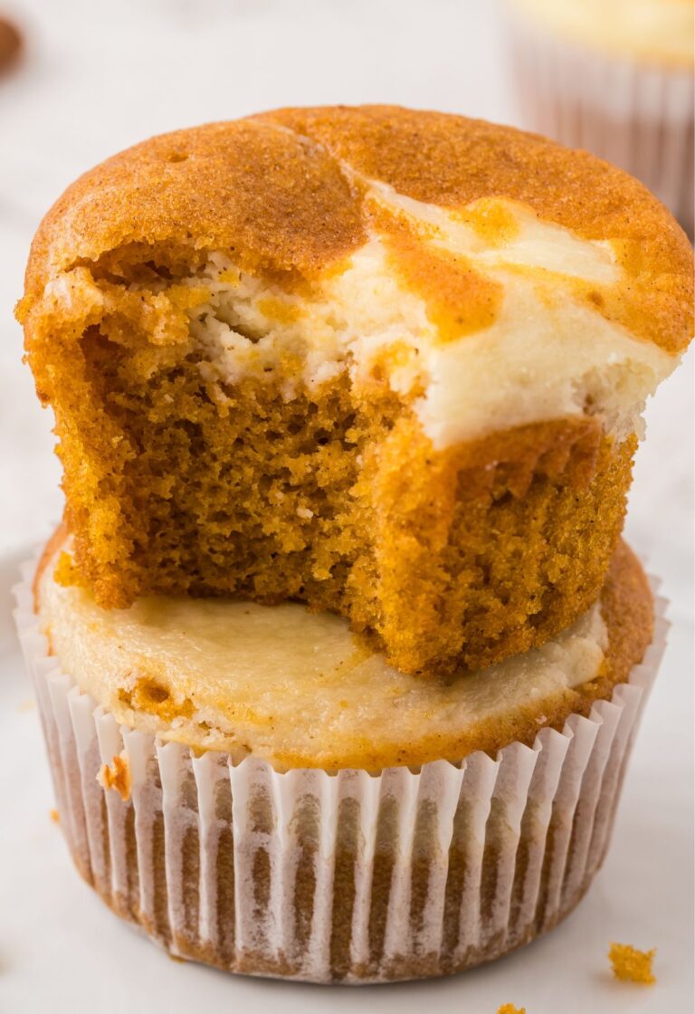 A stack of two muffins with the top one with a bite out of it