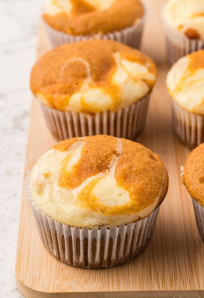 Side view of the baked pumpkin muffins on a wooden cutting board. 