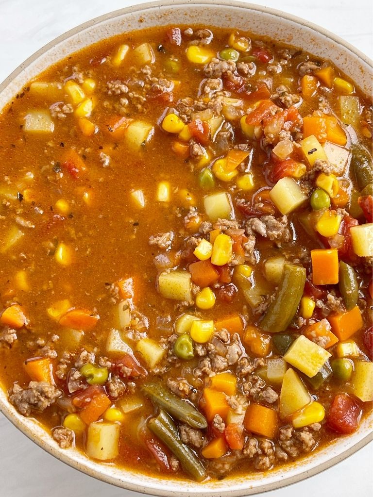 Bowl of hamburger soup with a white background.