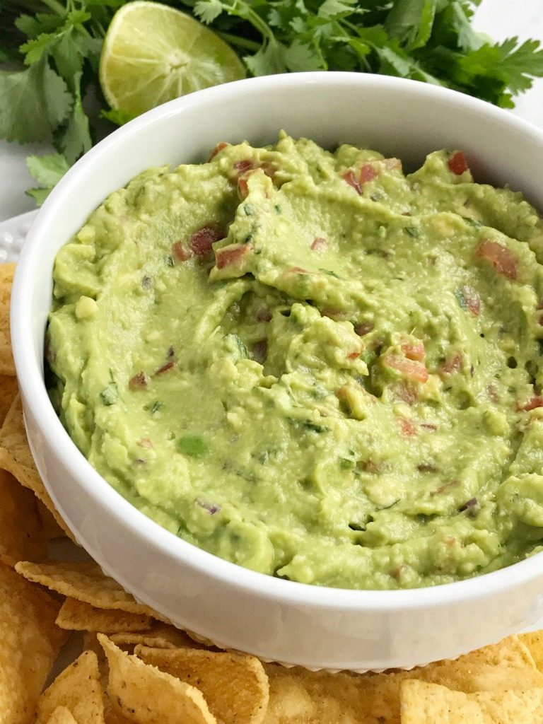 Salsa verde guacamole is loaded with tomato, cilantro, smashed avocado, jalapeno and salsa verde. Serve with tortilla chips for a delicious appetizer and a fan favorite for a game day party | Together as Family #guacamole #superbowlrecipes #appetizerrecipes #salsaverde #salsaverderecipes #healthyrecipes #recipeoftheday