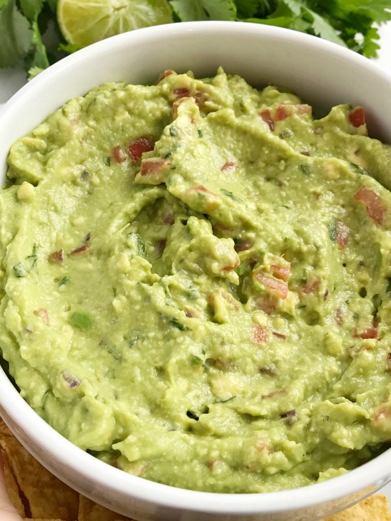 Salsa verde guacamole is loaded with tomato, cilantro, smashed avocado, jalapeno and salsa verde. Serve with tortilla chips for a delicious appetizer and a fan favorite for a game day party | Together as Family #guacamole #superbowlrecipes #appetizerrecipes #salsaverde #salsaverderecipes #healthyrecipes #recipeoftheday