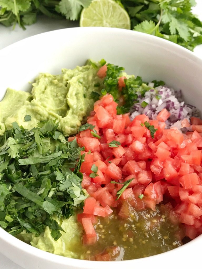 Salsa verde guacamole is loaded with tomato, cilantro, smashed avocado, jalapeno and salsa verde. Serve with tortilla chips for a delicious appetizer and a fan favorite for a game day party | Together as Family #guacamole #superbowlrecipes #appetizerrecipes #salsaverde #salsaverderecipes #healthyrecipes #recipeoftheday