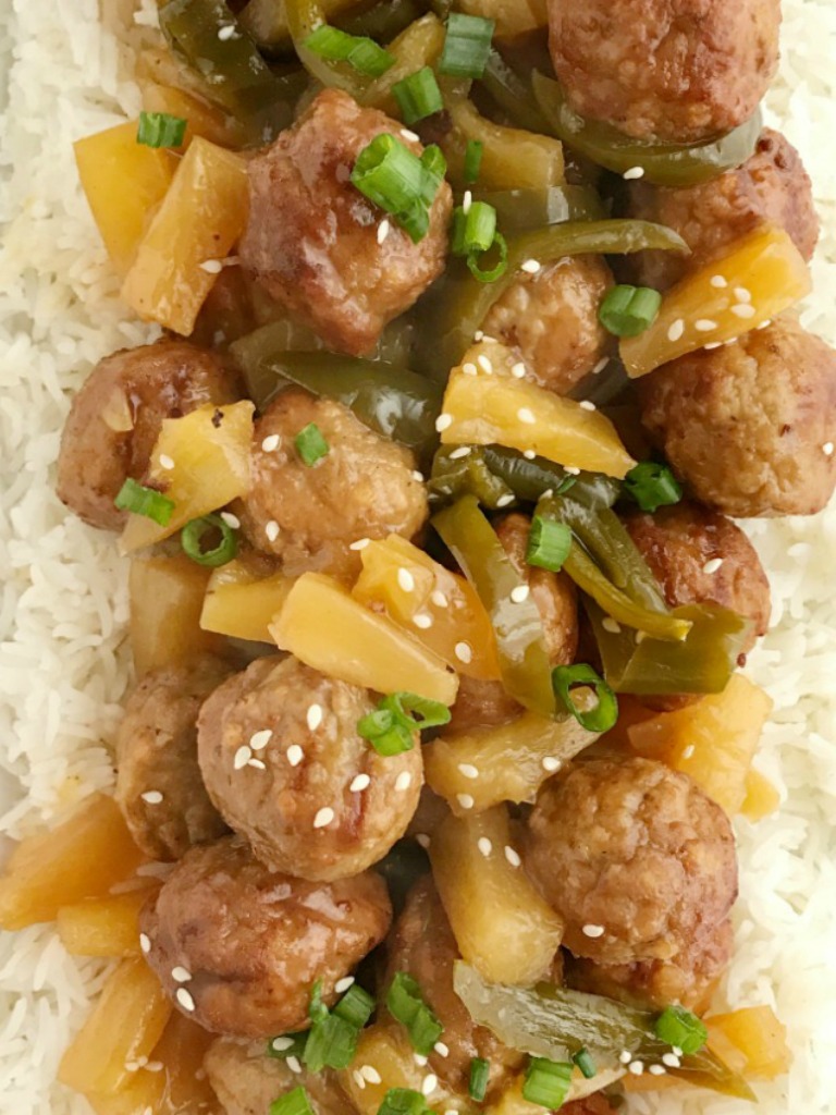 A picture of sweet and sour meatballs on top of white rice. 