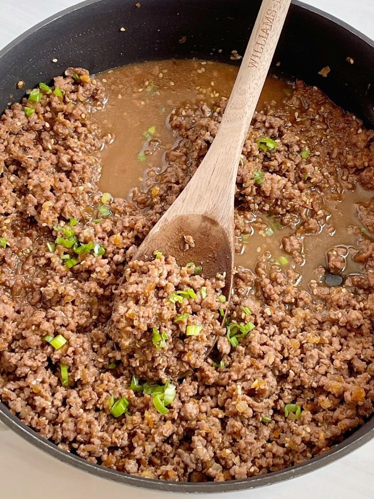 A skillet pan of ground beef teriyaki topped with green onions.