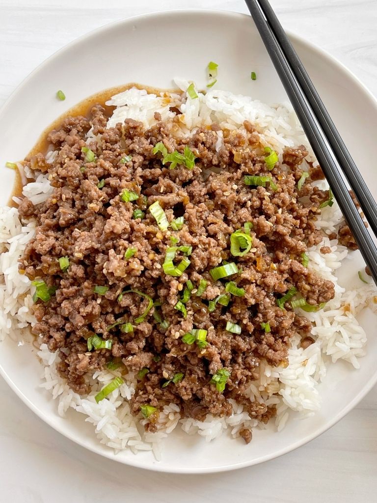 A white plate with ground beef teriyaki and chopsticks.