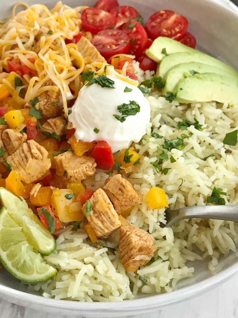 Chicken Fajita Burrito Bowls | Burrito Bowls | Mexican Food | Cinco de Mayo Recipes | Dinner | Chicken fajita burrito bowls are so easy to make at home! No need to go to restaurant for a burrito bowl anymore. Chicken, onion, peppers and seasonings cook in a skillet pan while cilantro lime rice simmers on the stove top. Serve with all your favorite burrito toppings for a healthy and delicious dinner that everyone can make their own of. #easydinnerrecipes #cincodemayo #burritobowls